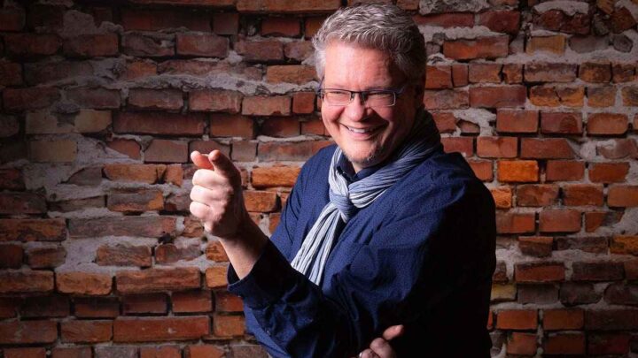 Lutz vor einer Steinwand zeigt auf dich